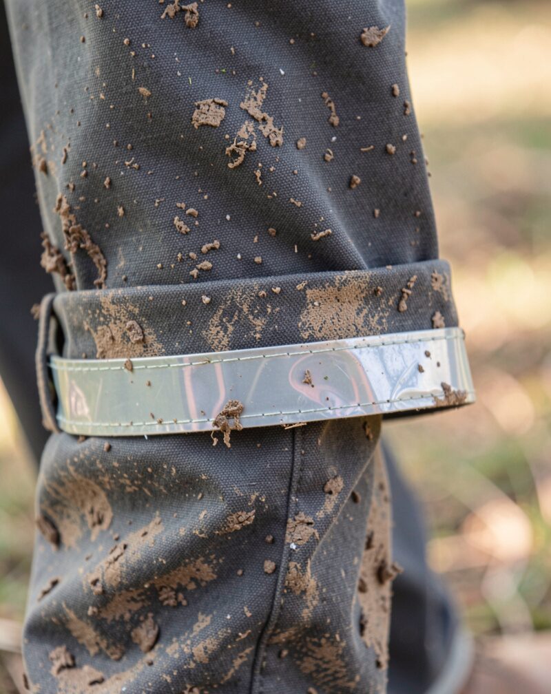Close-up of a muddy trouser cuff clipped with a reflective band